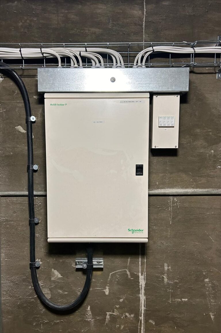 Commercial electrical panel installed on concrete wall with wiring connections.