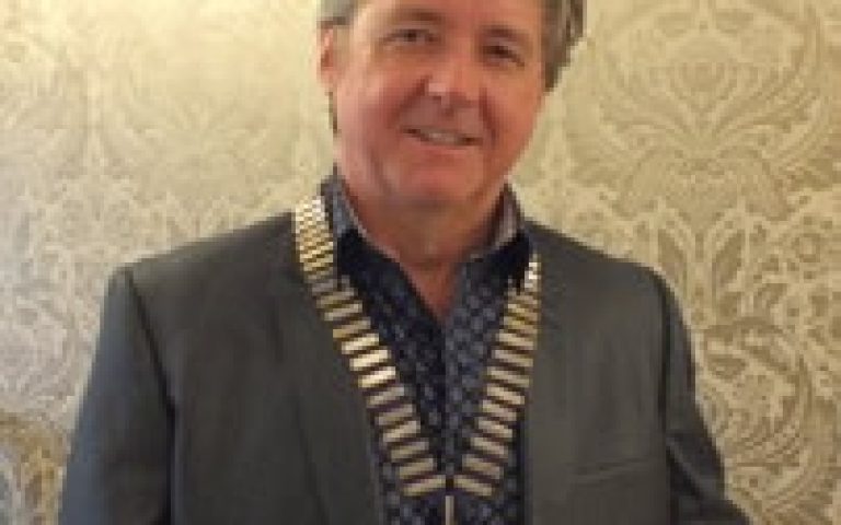 Derek Clark wearing a medal at a formal event, representing leadership in electrical industry.